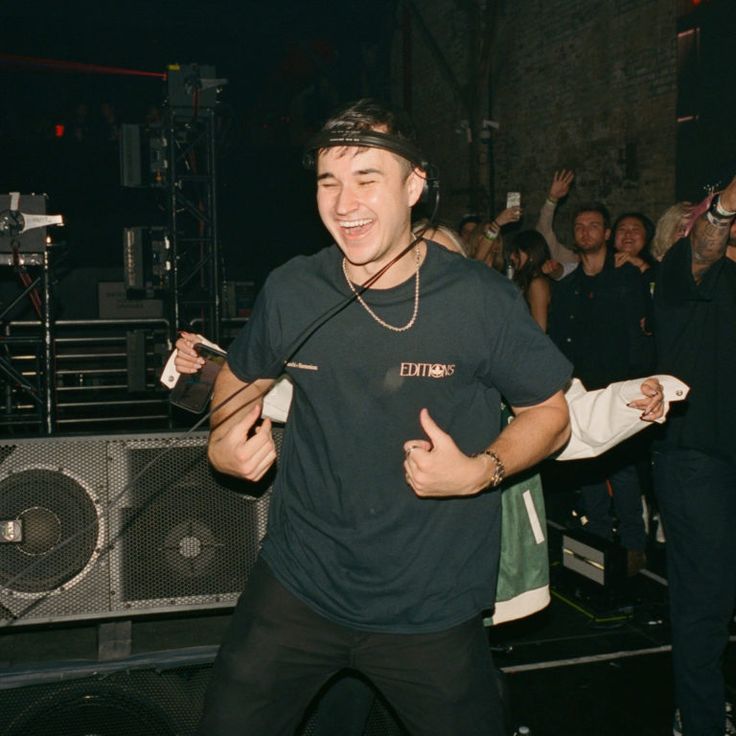 a man standing in front of a crowd holding a microphone and giving the thumbs up