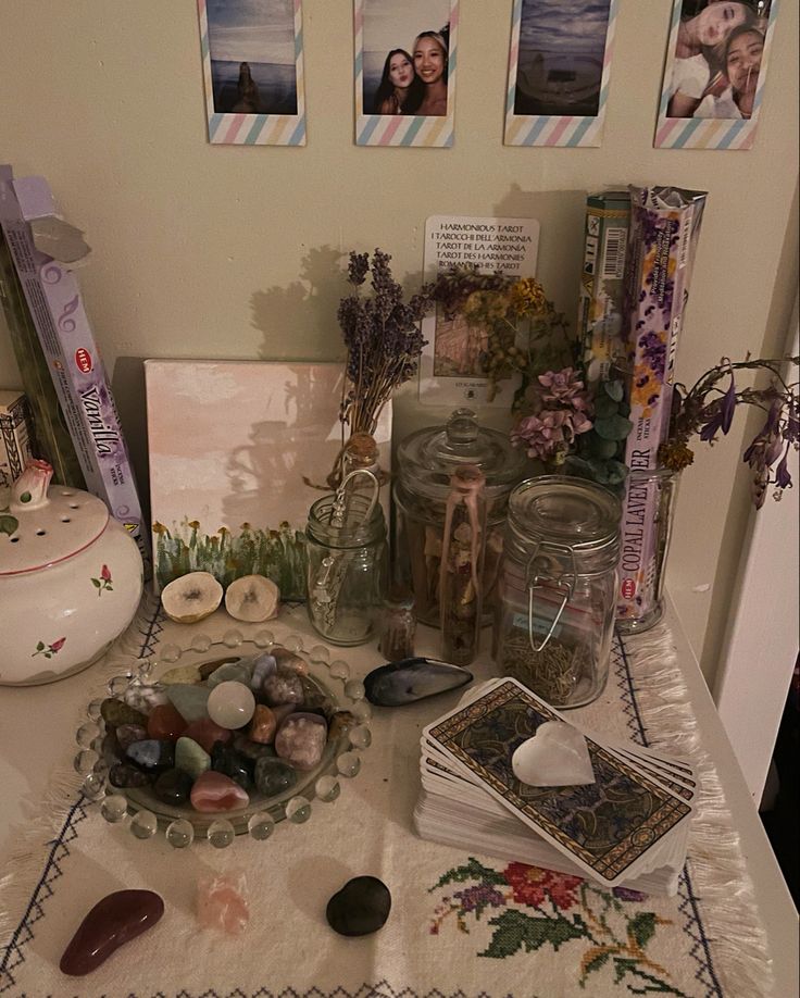 a table topped with lots of glass jars and rocks next to pictures on the wall