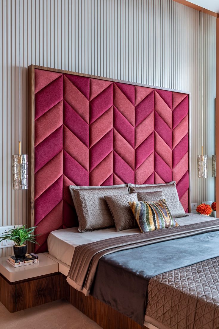 a bedroom with a pink headboard on the wall and pillows on the bed in front of it