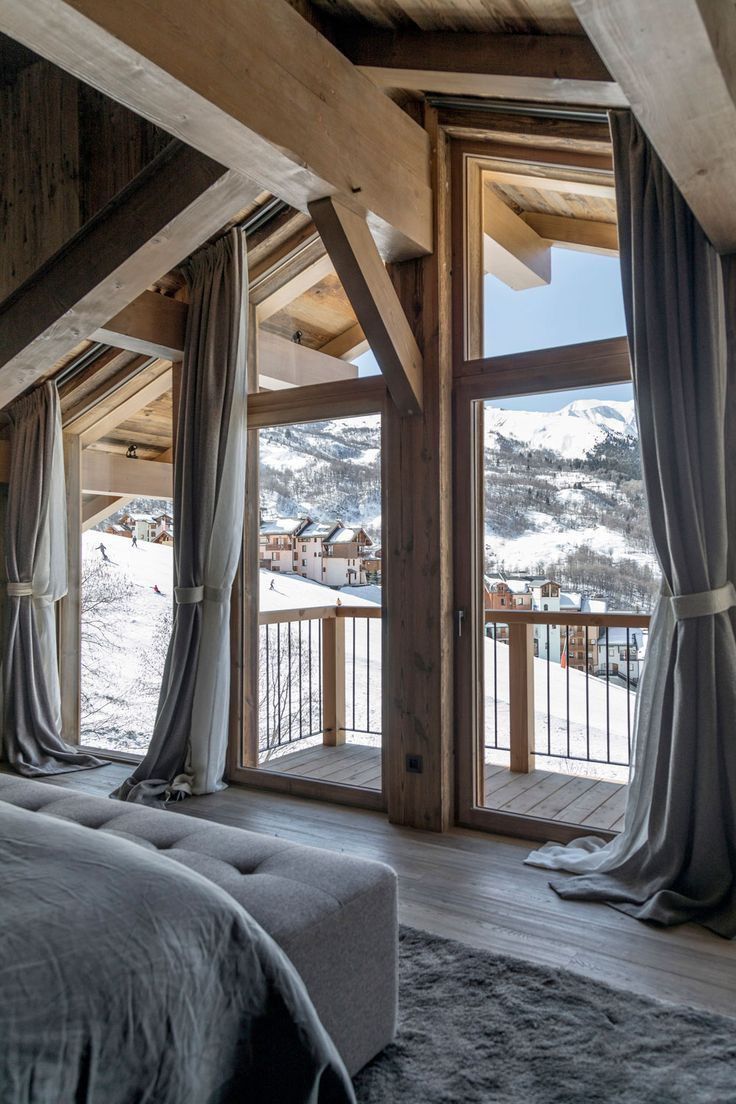 a bedroom with large windows overlooking the snow covered mountains