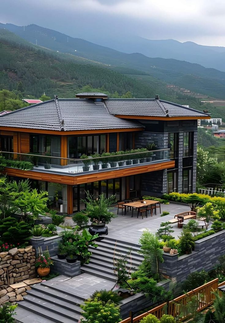 an aerial view of a large house surrounded by greenery and mountains in the background