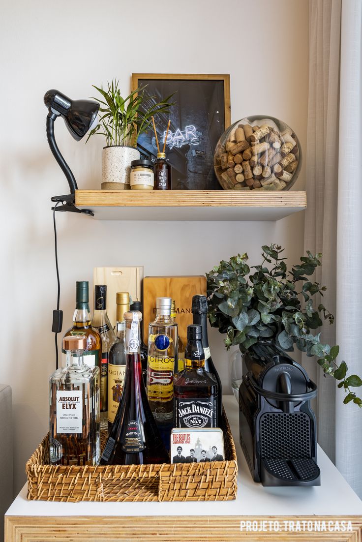 a shelf filled with liquor bottles next to a potted plant on top of a table