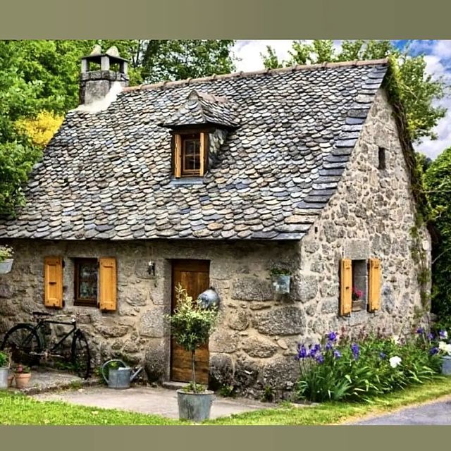 an old stone house with potted plants outside