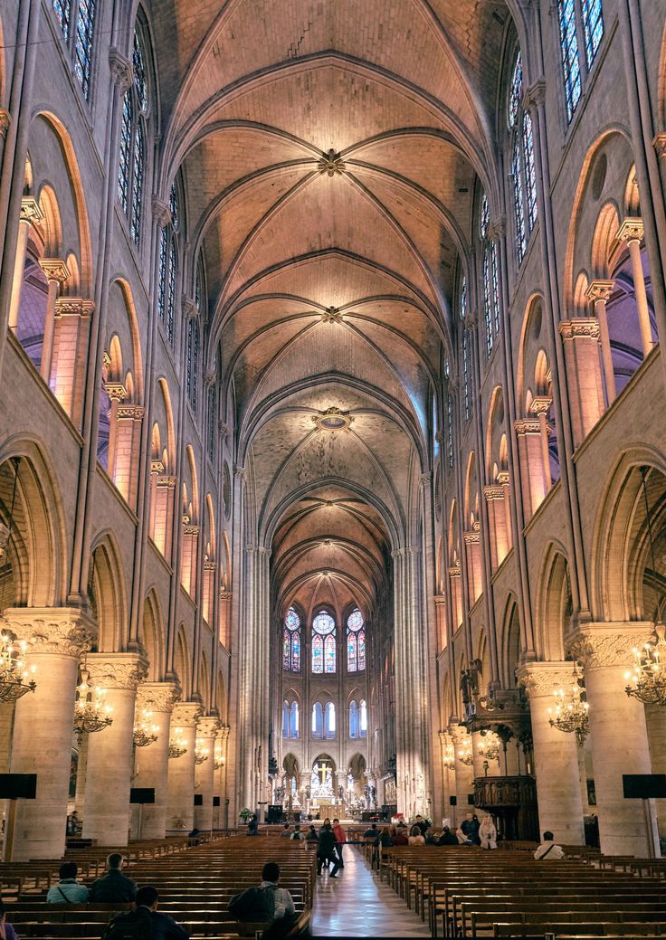 the inside of a large cathedral with pews and stained glass windows on both sides