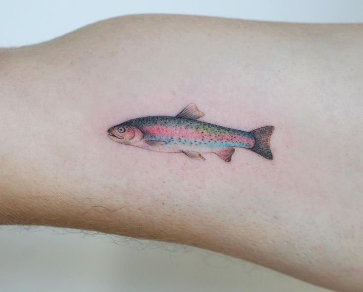 a rainbow colored fish tattoo on the arm