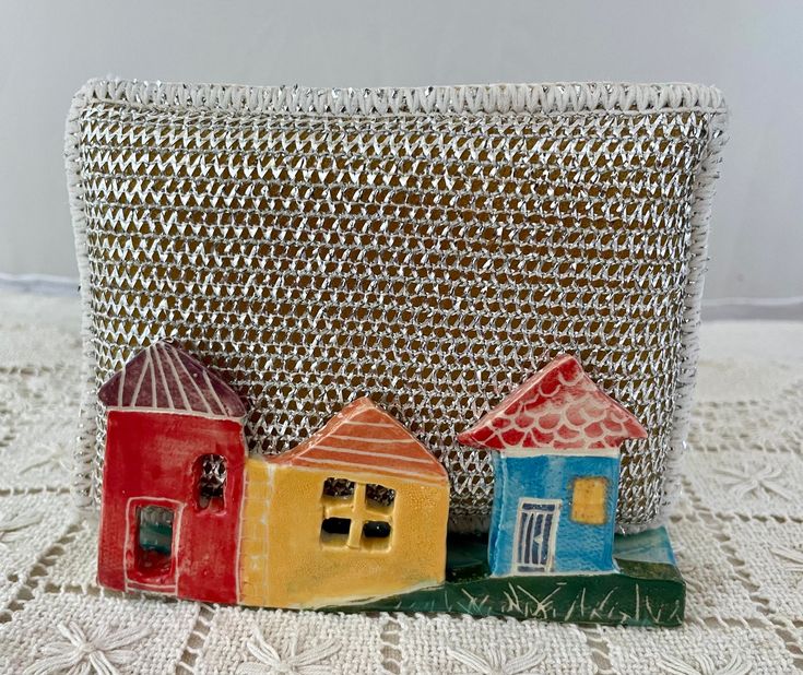 small ceramic houses sitting on top of a white doily covered table next to a basket