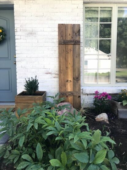 some plants are in front of a white brick house