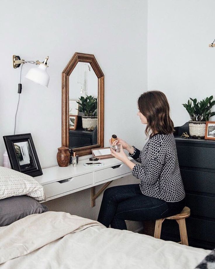 a woman sitting at a desk in front of a mirror