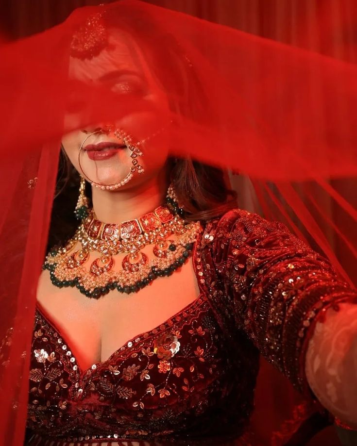 a woman in a red dress and veil with jewelry on her neck, wearing an elaborate necklace