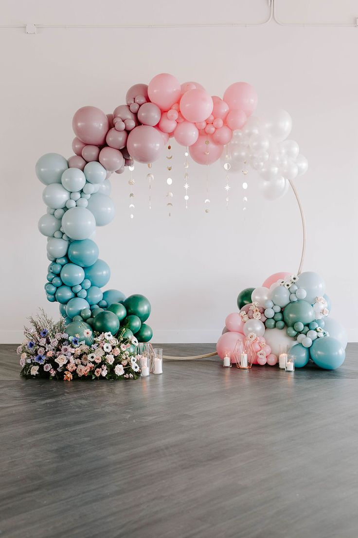 the balloon arch is decorated with pastel colors and balloons for a baby's first birthday