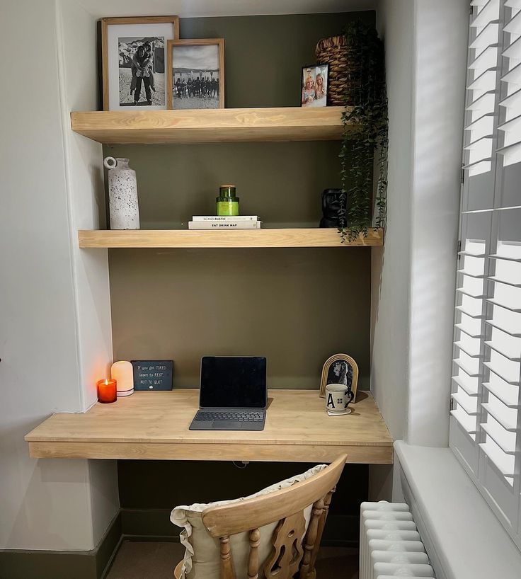 a laptop computer sitting on top of a wooden desk next to a window with shutters