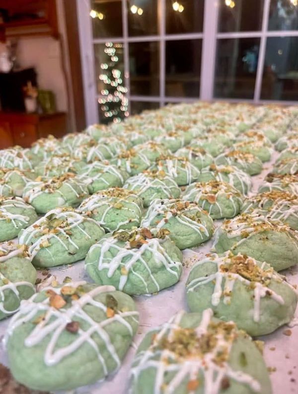 green cookies with white icing and sprinkles sitting on top of a table