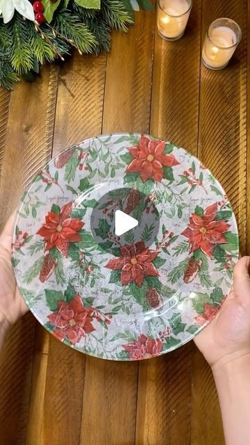 someone is holding a plate decorated with poinsettis and holly on the table