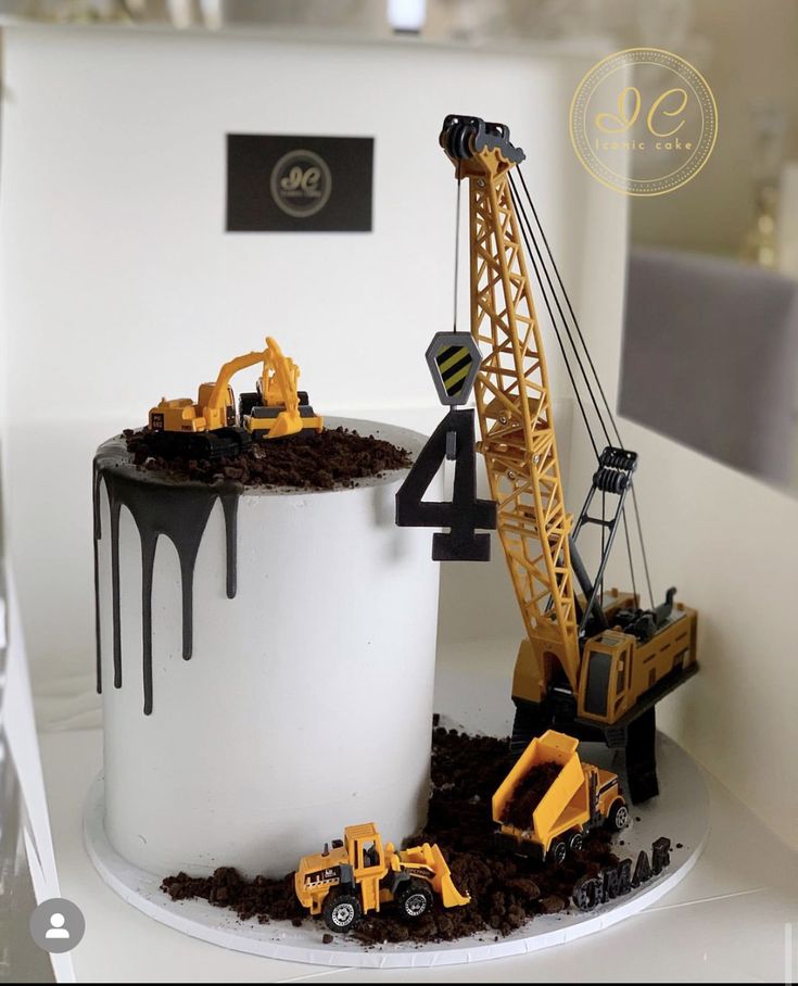 a birthday cake with construction vehicles and dirt on the bottom, sitting on a table