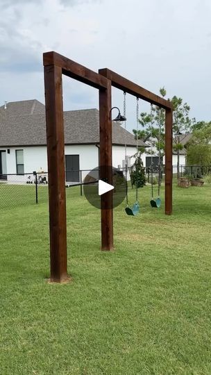 an outdoor play area with swings and slides in the grass, next to a house