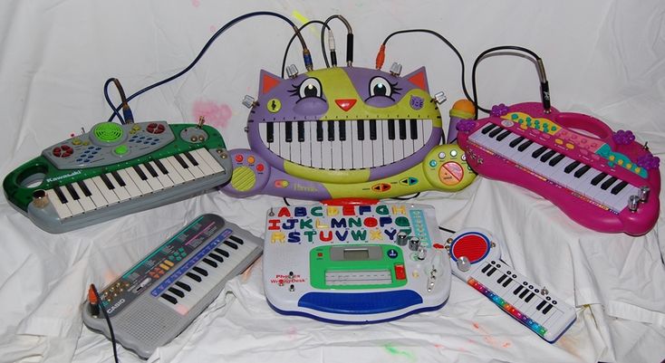 an assortment of musical instruments and toys on a white sheeted surface, including a keyboard