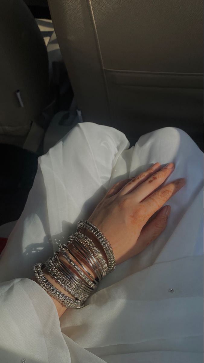 a woman's hand with rings and bracelets on her arm sitting in the back seat of a car