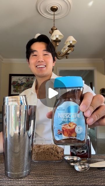 a man holding up a jar of peanut butter next to a shaker and cup