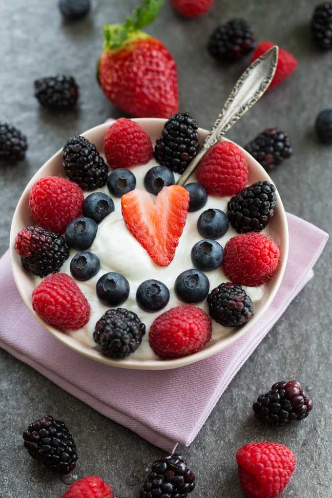 a bowl filled with berries and yogurt on top of a pink napkin