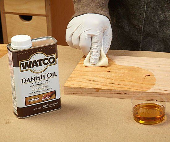 a person in white gloves waxing a piece of wood on top of a table