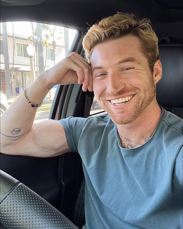 a man sitting in the back seat of a car smiling and looking at the camera