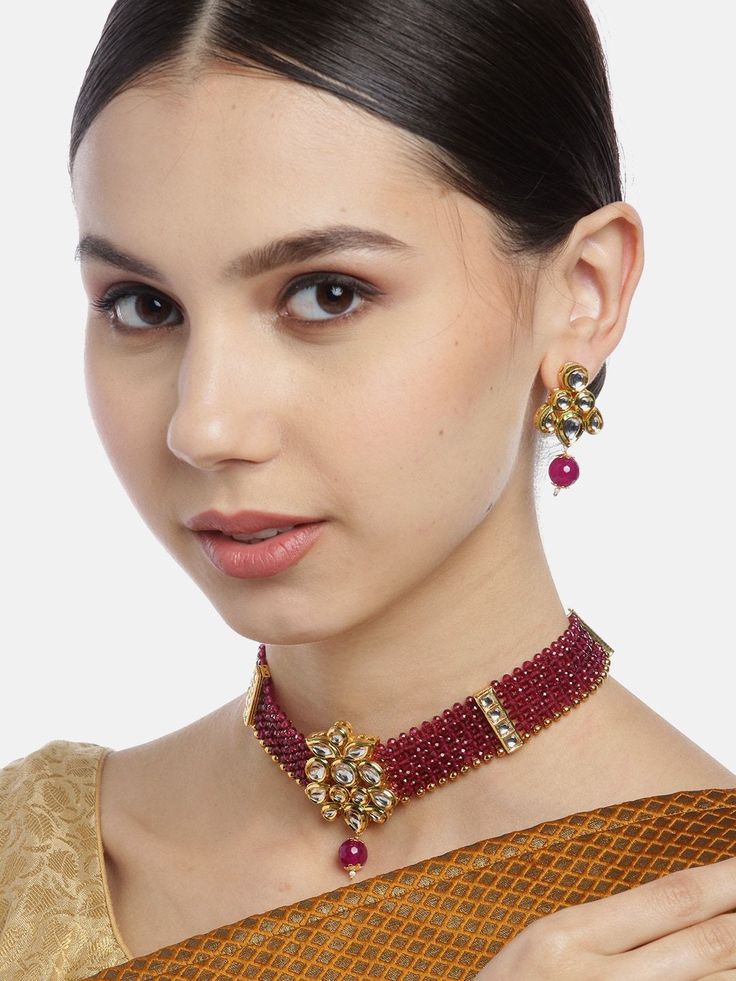 This beautiful jewelry set consists of a handcrafted choker necklace and a pair of matching earrings. The maroon multi-layer stones & beaded choker necklace shown here comes with kundan stone studs, is gold-plated, and secured with an adjustable drawstring closure. A pair of matching oversized circular studs come secured with a post and back closure. This gorgeous statement piece can add impact to any outfit for any festive occasion! Product color may vary based on the monitor or screen you are Festive Temple Jewelry Choker, Festive Choker Jewelry, Festive Temple Jewelry Sets With Choker, Festive Temple Jewelry Choker Sets, Adjustable Temple Jewelry Sets For Festive Occasions, Festive Adjustable Temple Jewelry Sets, Festive Choker Jewelry Sets For Celebration, Festive Temple Jewelry Sets, Festive Celebration Jewelry Sets With Choker