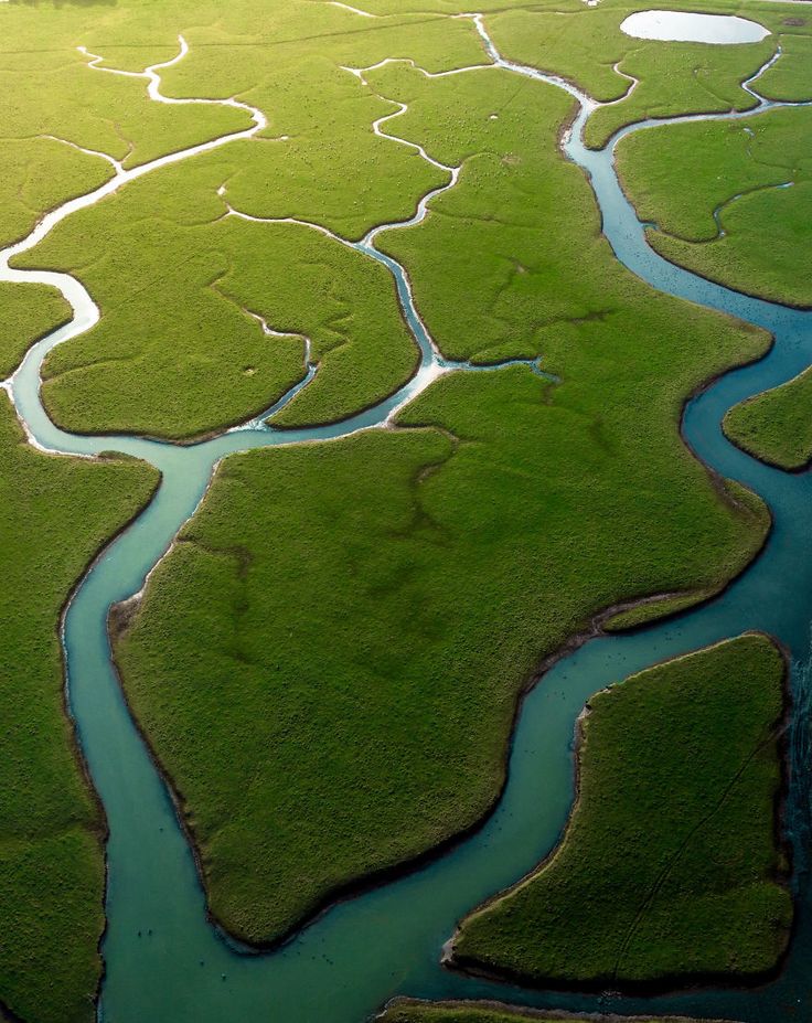 an aerial view of a river running through green land