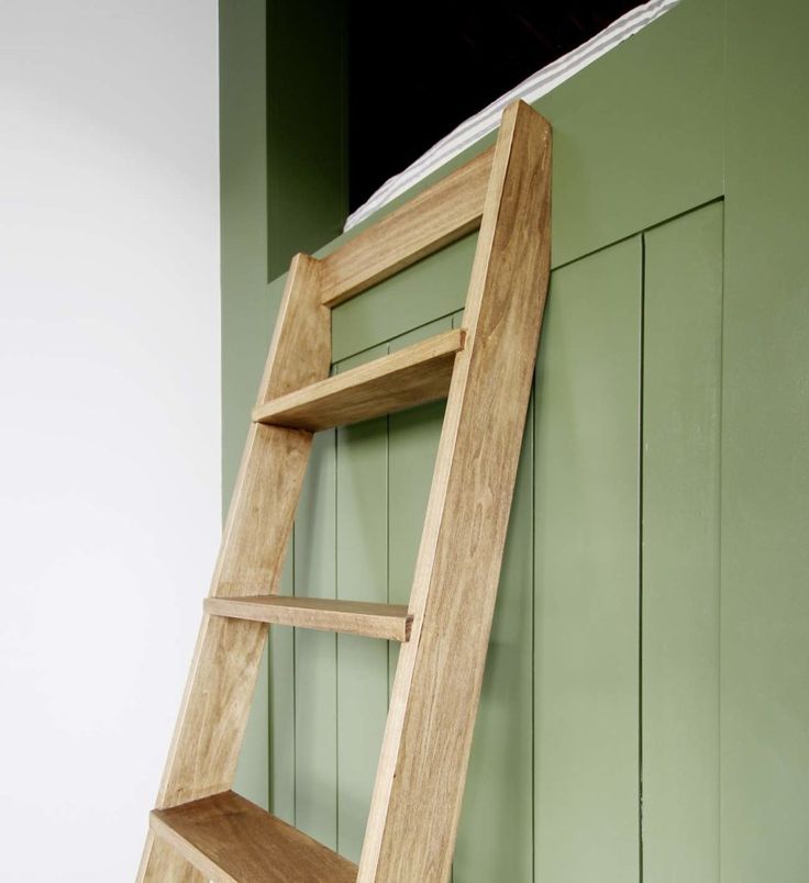 a wooden ladder leaning against a green wall