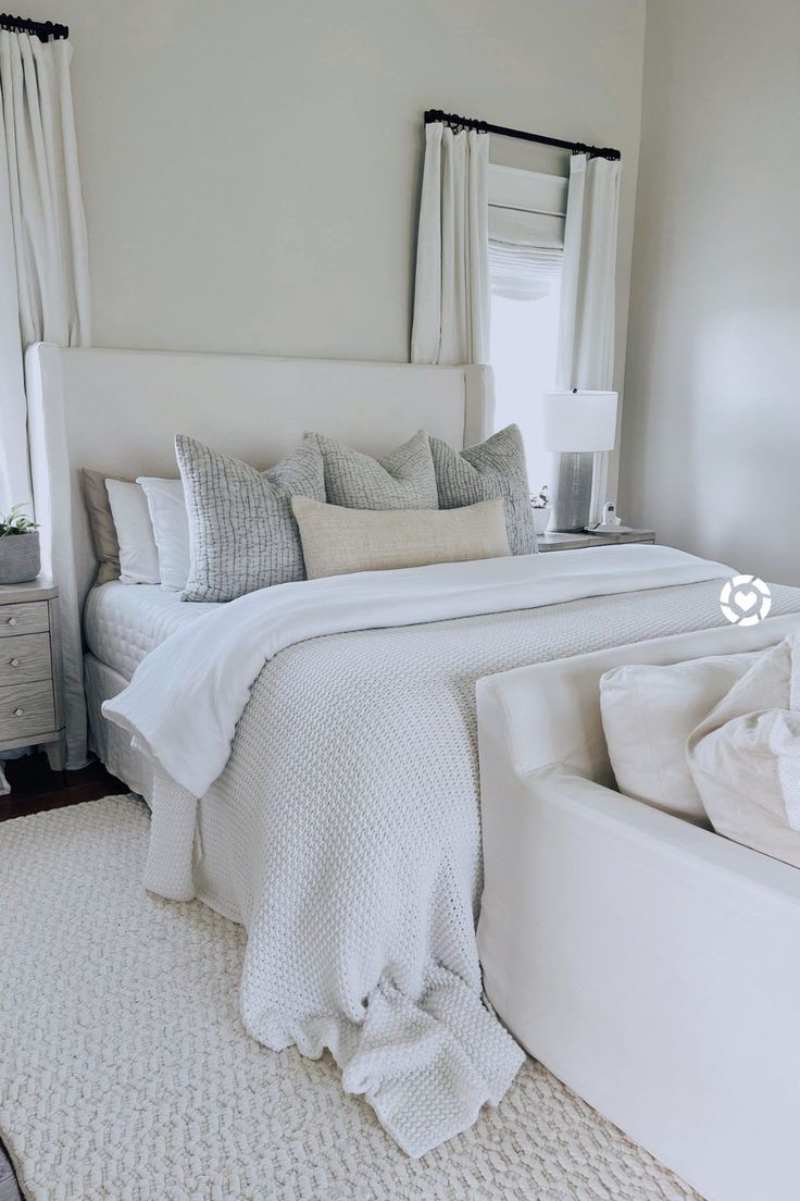 a white bed sitting in a bedroom next to a window