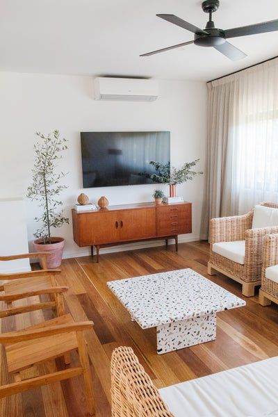 a living room with wicker furniture and a flat screen tv mounted on the wall