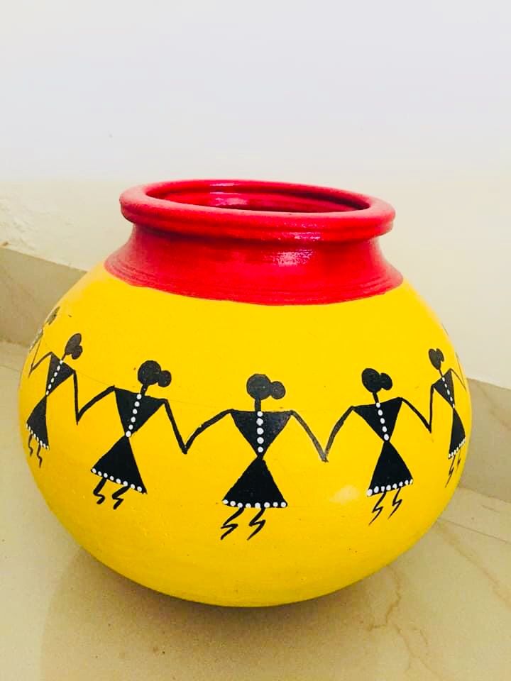 a yellow and red vase sitting on top of a counter next to a white wall