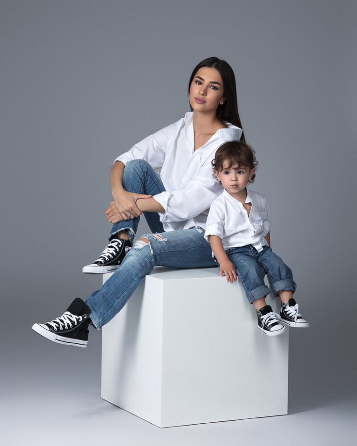 a woman and child sitting on top of a white cube