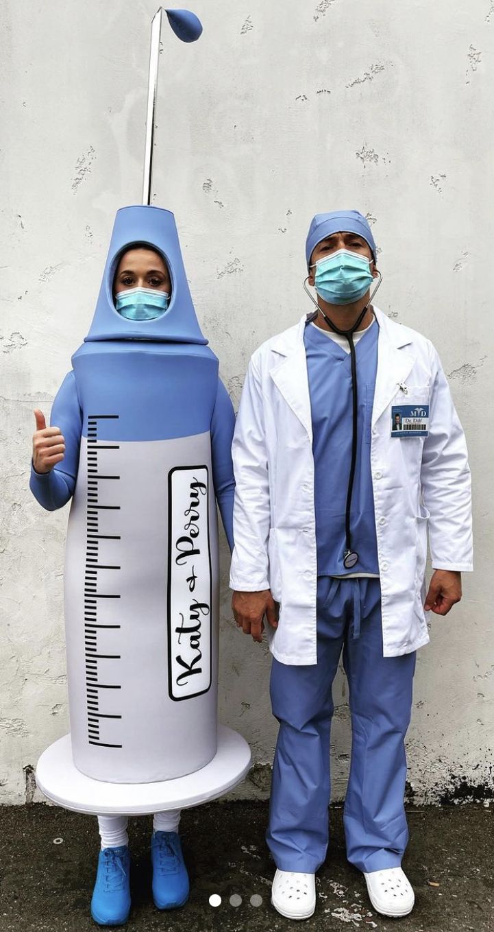 two doctors in scrubs stand next to a fake rocket ship with a thermometer on it