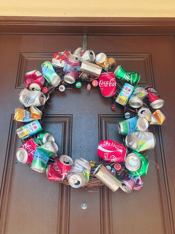 a wreath made out of cans and cans on the front door is hanging from a brown door