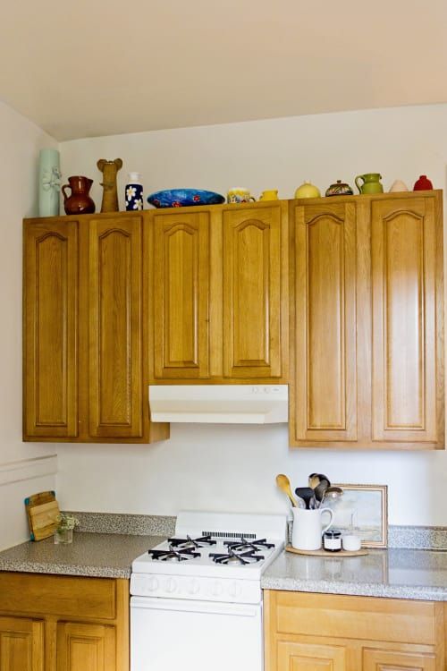 a white stove top oven sitting inside of a kitchen next to wooden cupboards and counter tops