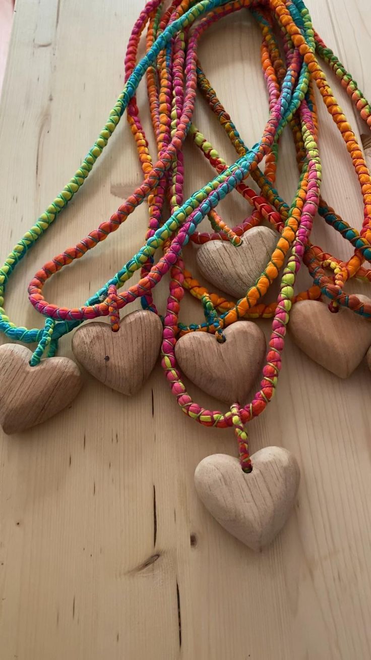 several wooden hearts hanging from a string on top of a wood table next to other heart shaped beads