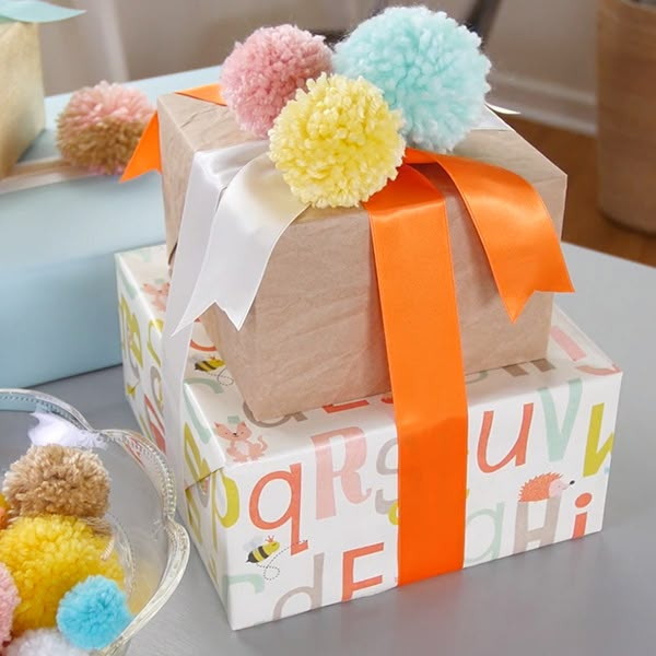 two boxes with pom - poms on top of each one are sitting on a table