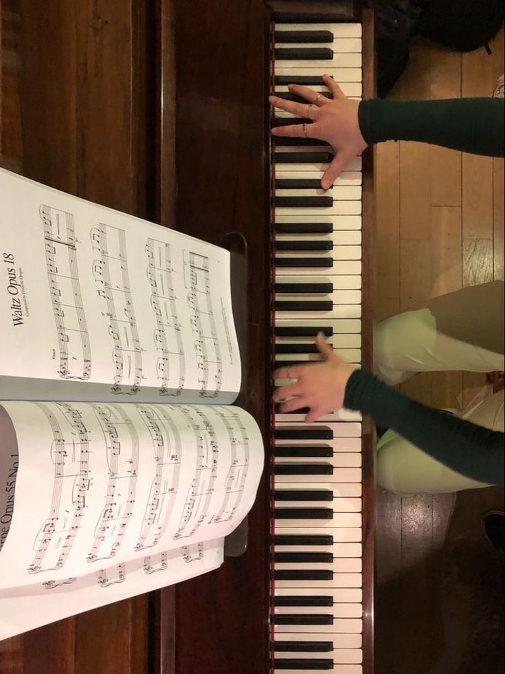 two people are playing the piano with sheet music