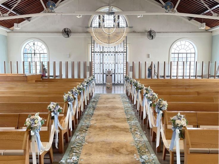 an empty church with wooden pews and flowers on the aisle