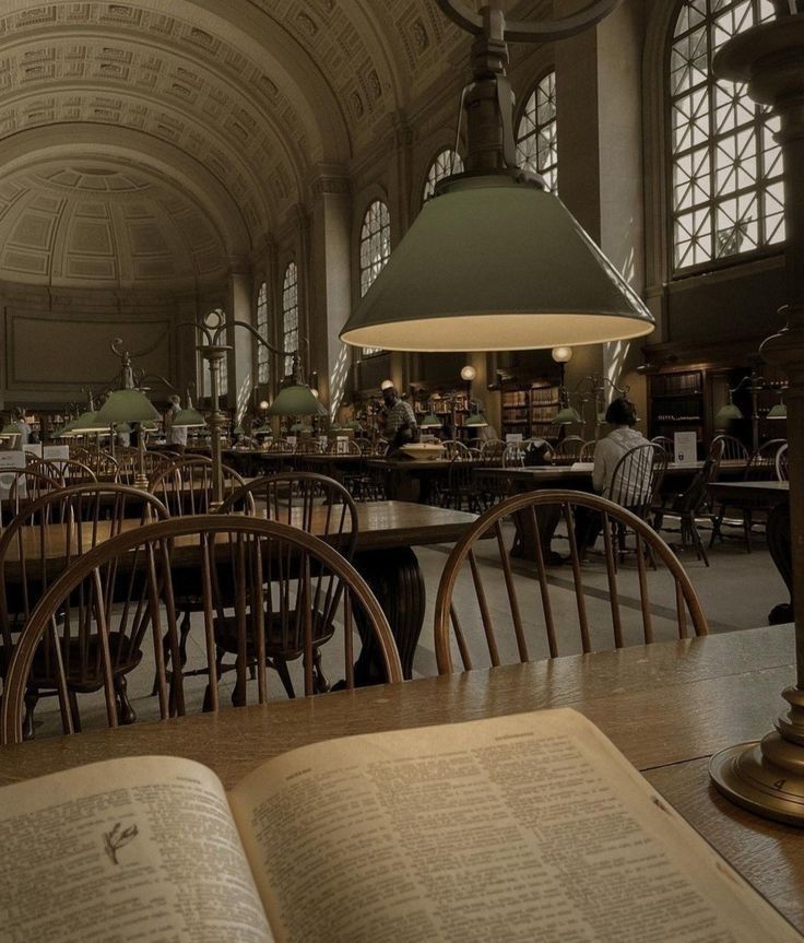 an open book sitting on top of a wooden table in a room filled with tables and chairs