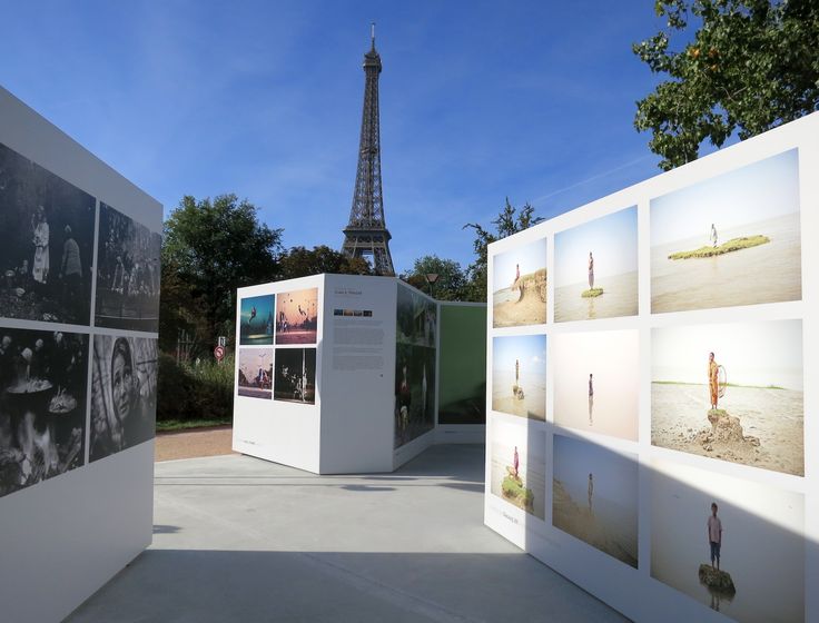 several photographs are displayed in front of a wall with the eiffel tower in the background