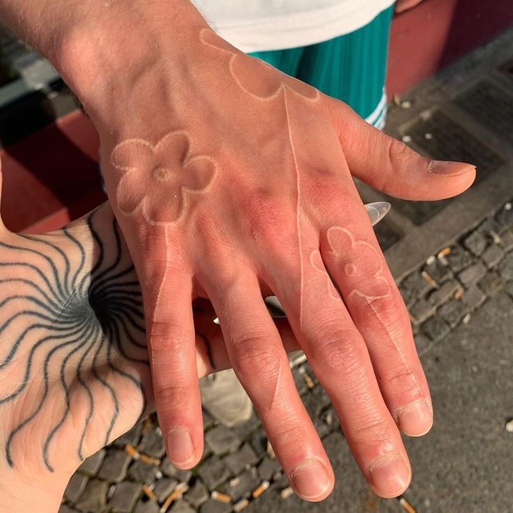 two people with tattoos on their hands holding each other's hand and touching one another