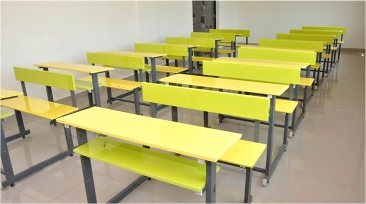 rows of yellow school desks in an empty classroom