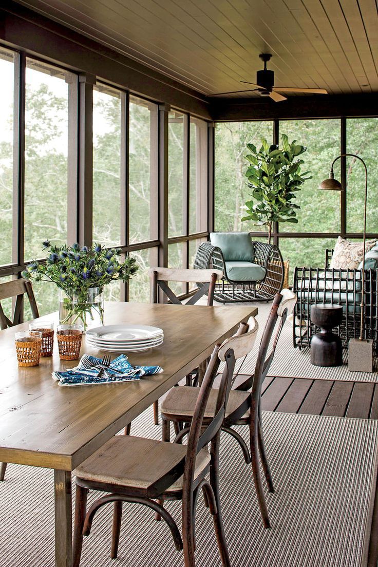 a wooden table sitting on top of a patio next to a tall glass wall with lots of windows