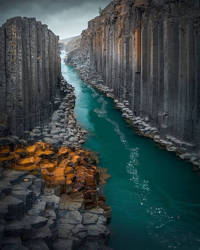 a river running between two rocky mountains next to a body of water with rocks on both sides