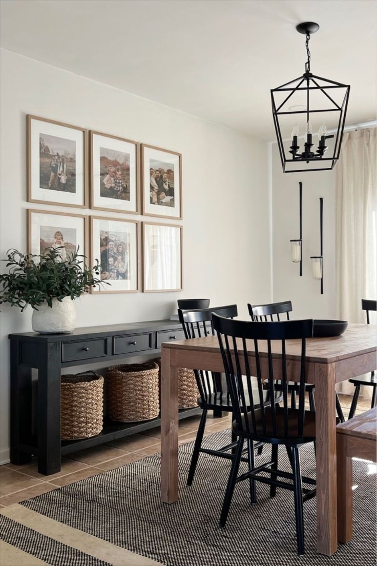 a dining room table with four chairs and a bench in front of a window that has pictures on the wall