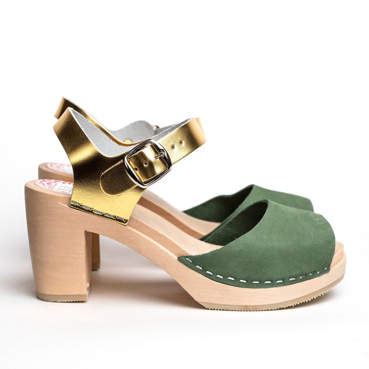 Woman high heeled wooden sandal. Moss green nubuck leather on front part. Gold leather at heel. Wooden sole, 8 cm heels. Handmade in Sweden. The shoe stays true to European sizes. Marks on the wooden sole that might appear with use can easily be removed with a fine sand paper. Do you have questions or need additional information? Please contact us on sofie@liliandlala.com. www.liliandlala.com Lili & Lala was founded by Swedish Alexandra Giertz in India in 2014. Lili & Lala is now Stockho Green Open Toe Sandals With Sculpted Heel, Green Sandals With Sculpted Heel, Green Sandals With Sculpted Open Heel, Green Open Toe Mules With Leather Sole, Green Leather Sole High Heels, Green Sandals With Sculpted Block Heel, Green Closed Toe Heels With Leather Sole, Green Leather Open Heel Mules, Green Leather Open-heel Mules