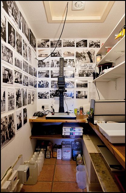 a room with many pictures on the wall and shelves full of boxes, jars, containers