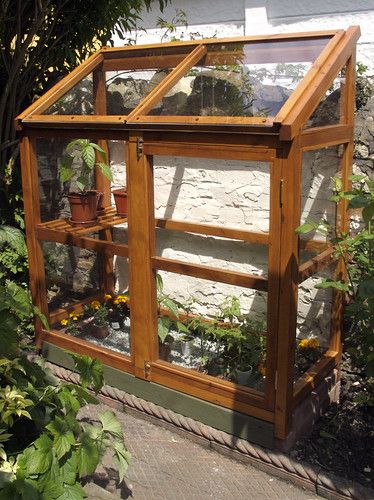 a small wooden greenhouse with plants growing inside