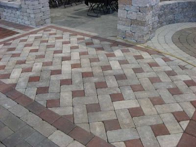 an outdoor patio with brick pavers and stone pillars